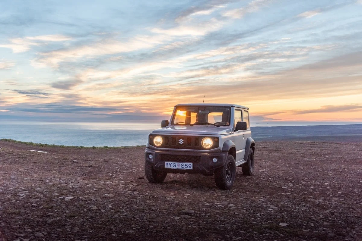 Petit 4x4 Suzuki garé sur sol volcanique au coucher du soleil