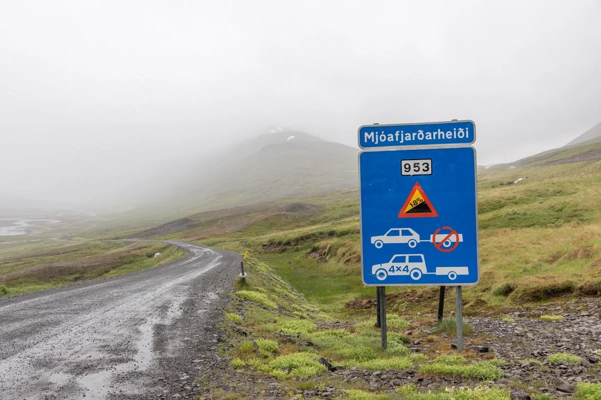 Panneau routier bleu indiquant une piste 4x4 sous la brume