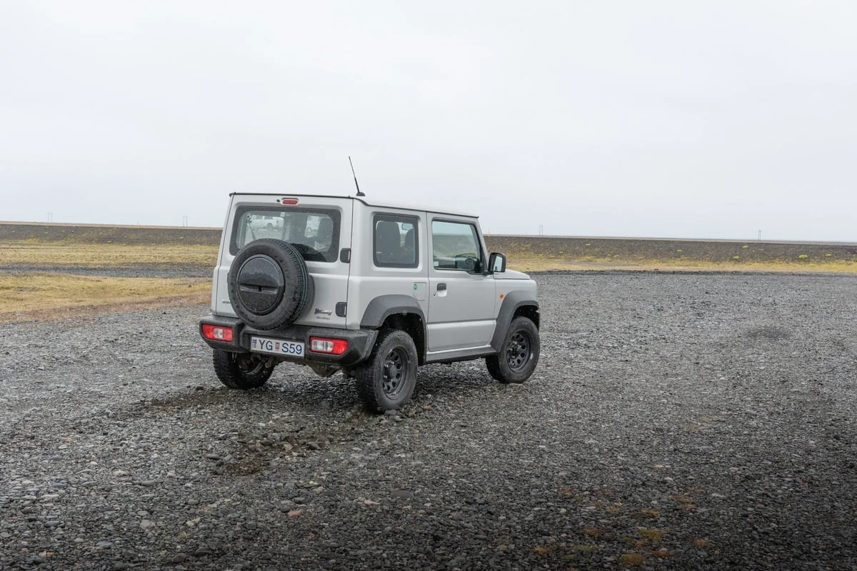 Petit SUV vu de dos sur un terrain de graviers sombres