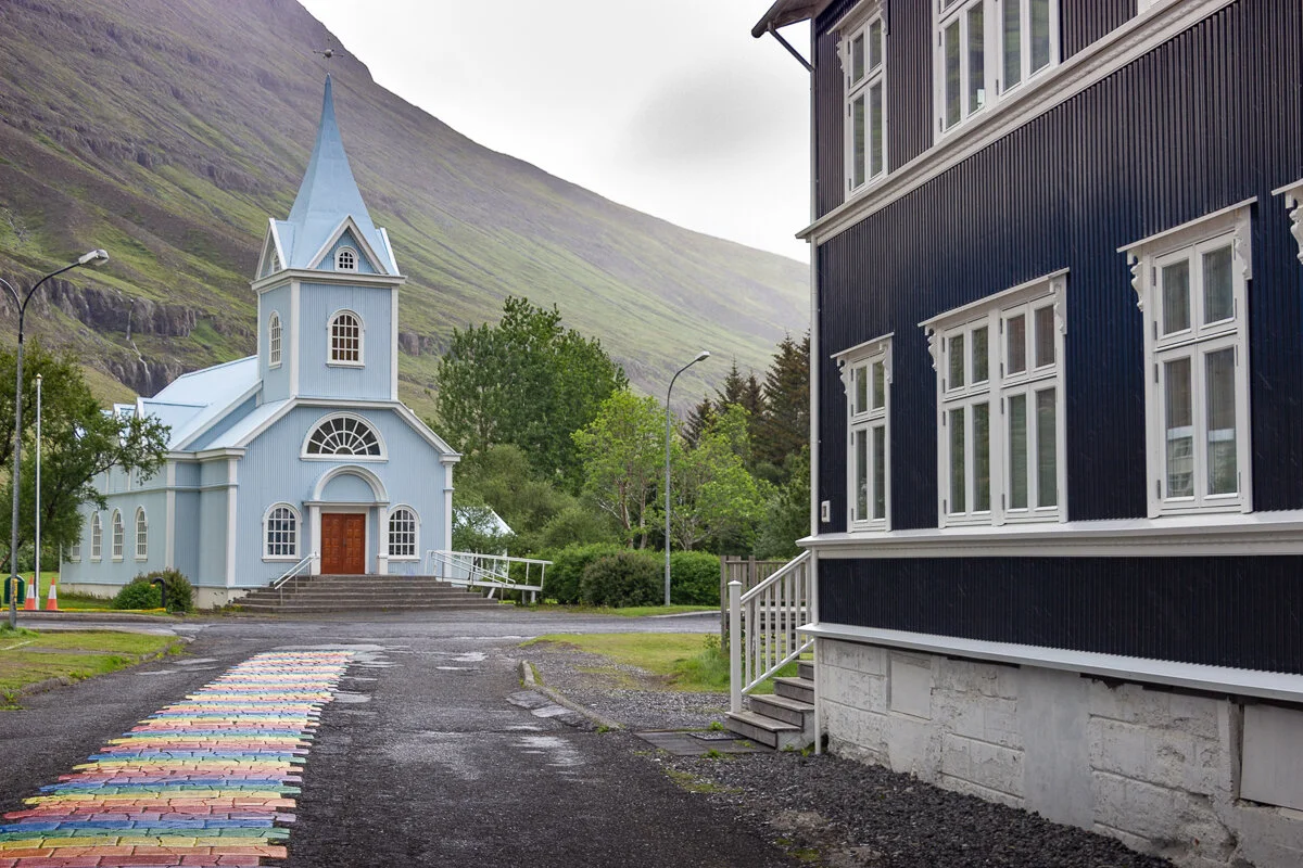 une église au bout d'un chemin aux couleurs de l'arc en ciel