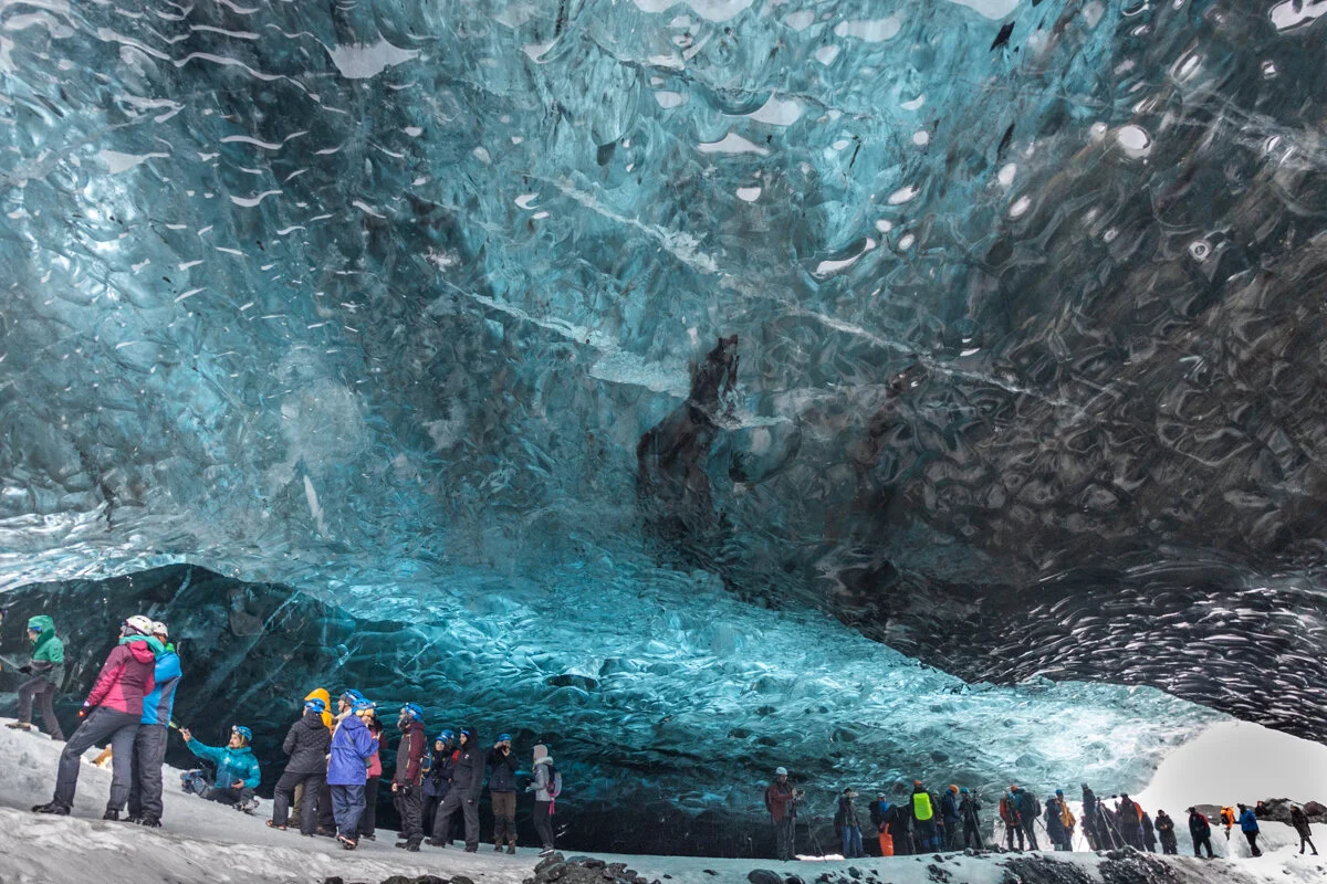 des touristes observent le décor dans une grotte de glace bleue