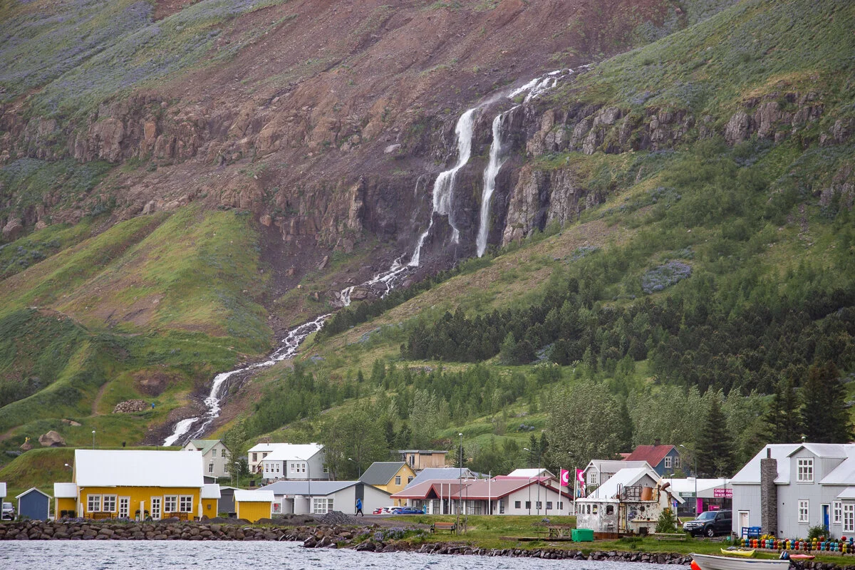 une cascade coule le long d'une montagne verte au-dessus de Seydisfjordur