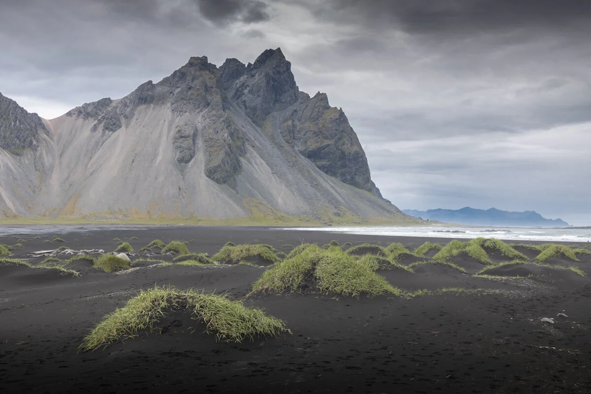 montagne aux pentes noires avec végétation verte au premier plan sur la plage de Stokksnes