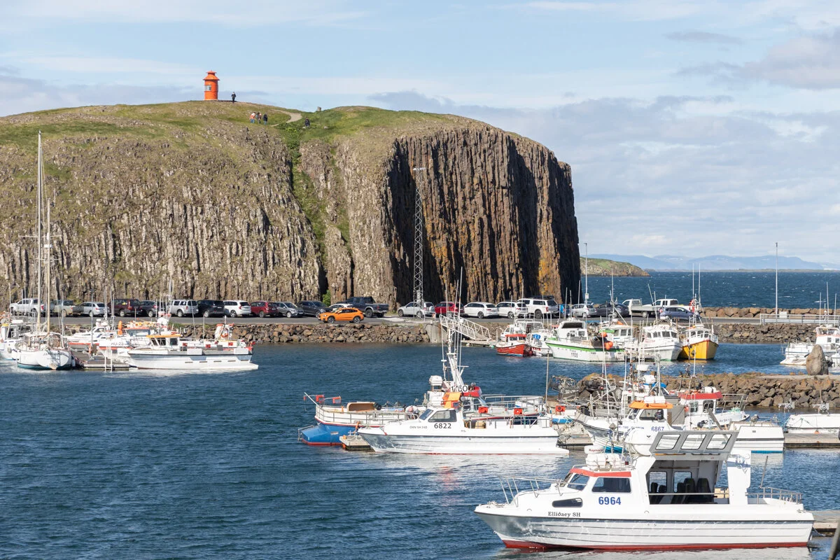 des bateaux de pêche amarrés près d'une falaise basaltique côtière