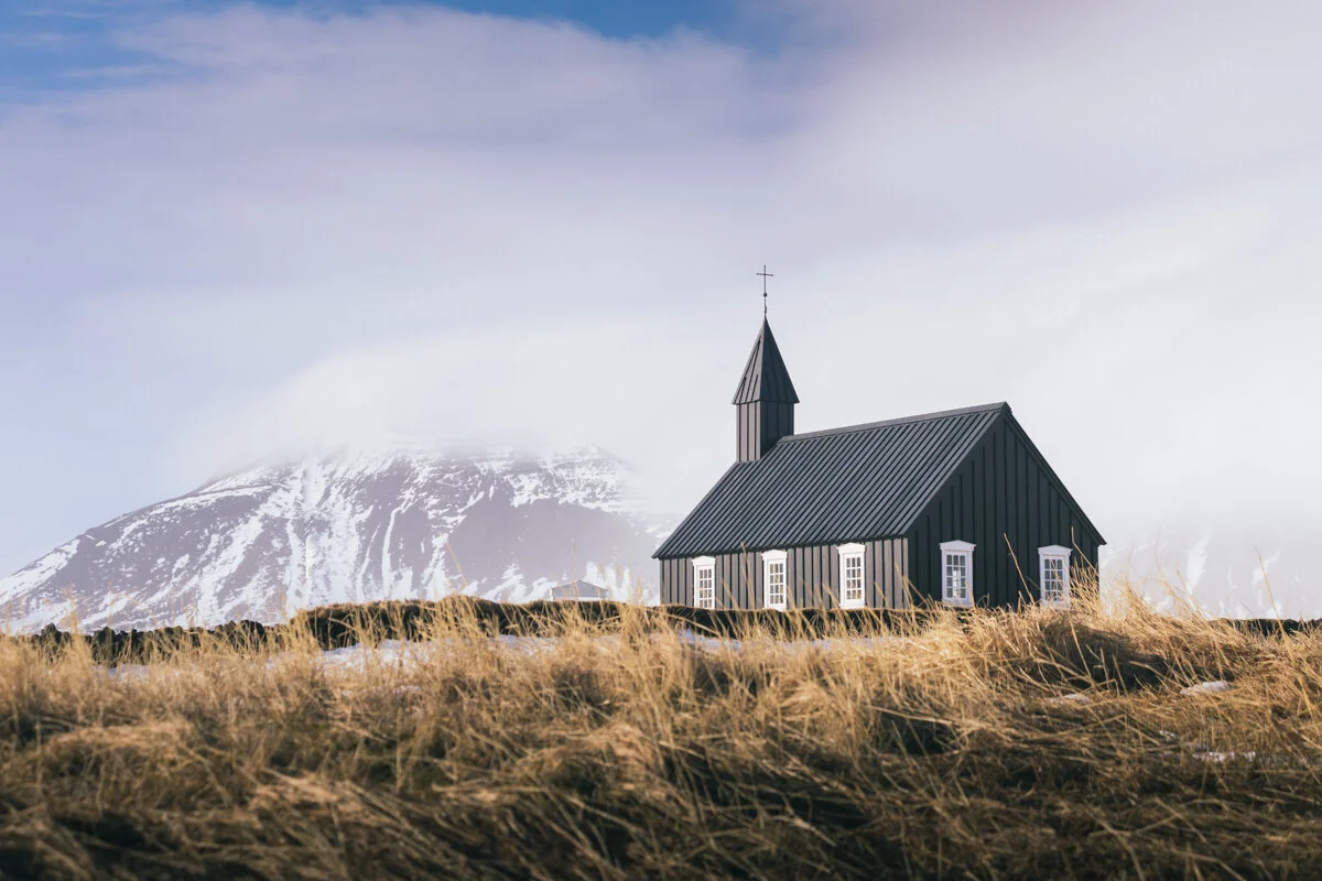 église noire en bois sur une colline herbeuse