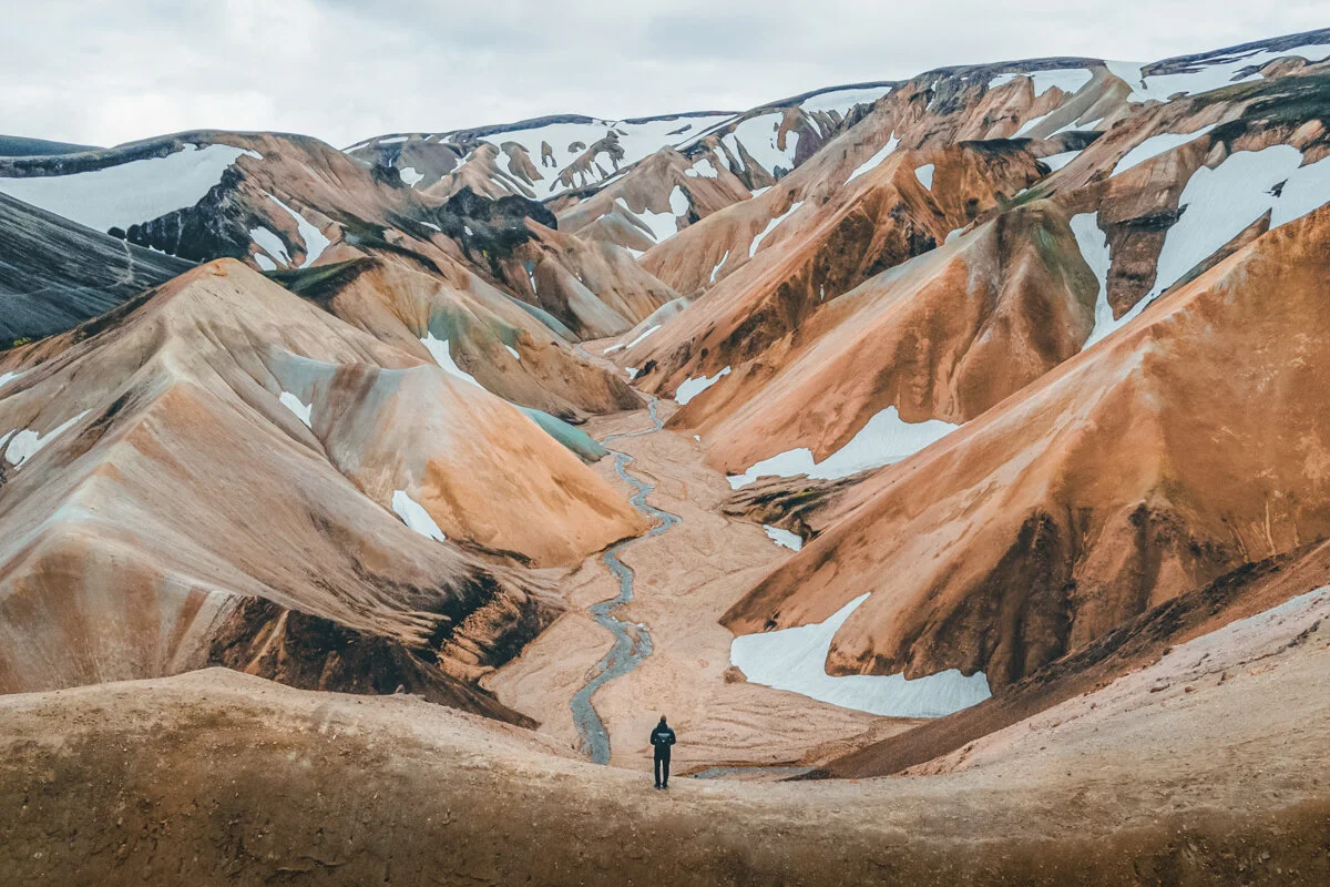 personne marchant dans des montagnes aux couleurs multicolores à Landmannalaugar