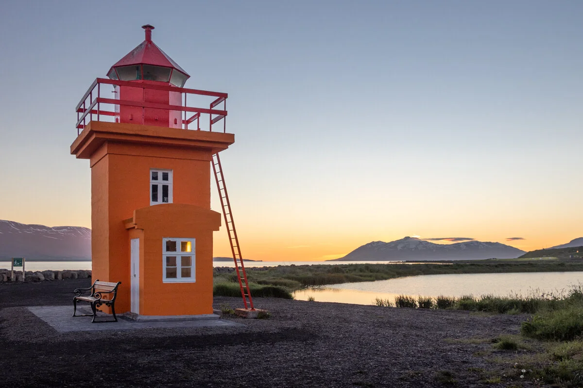 phare rouge et orange au bord de l'eau au coucher du soleil