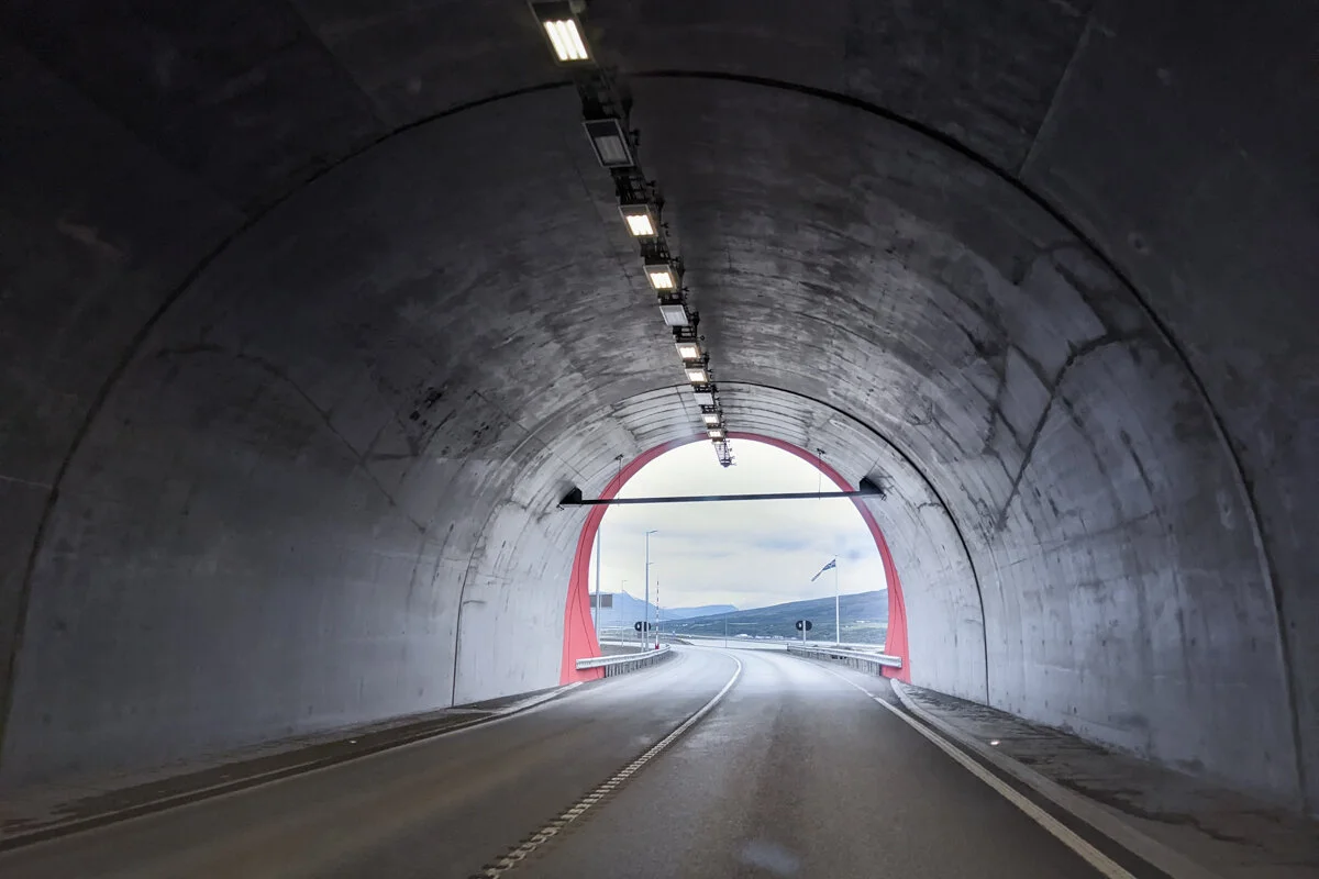 un tunnel routier avec une voiture rouge à l'horizon