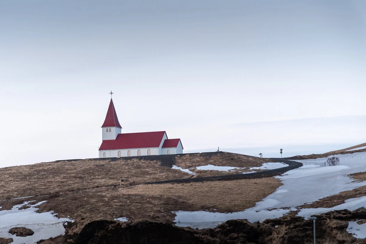 église rouge et blanche sur une colline enneigée