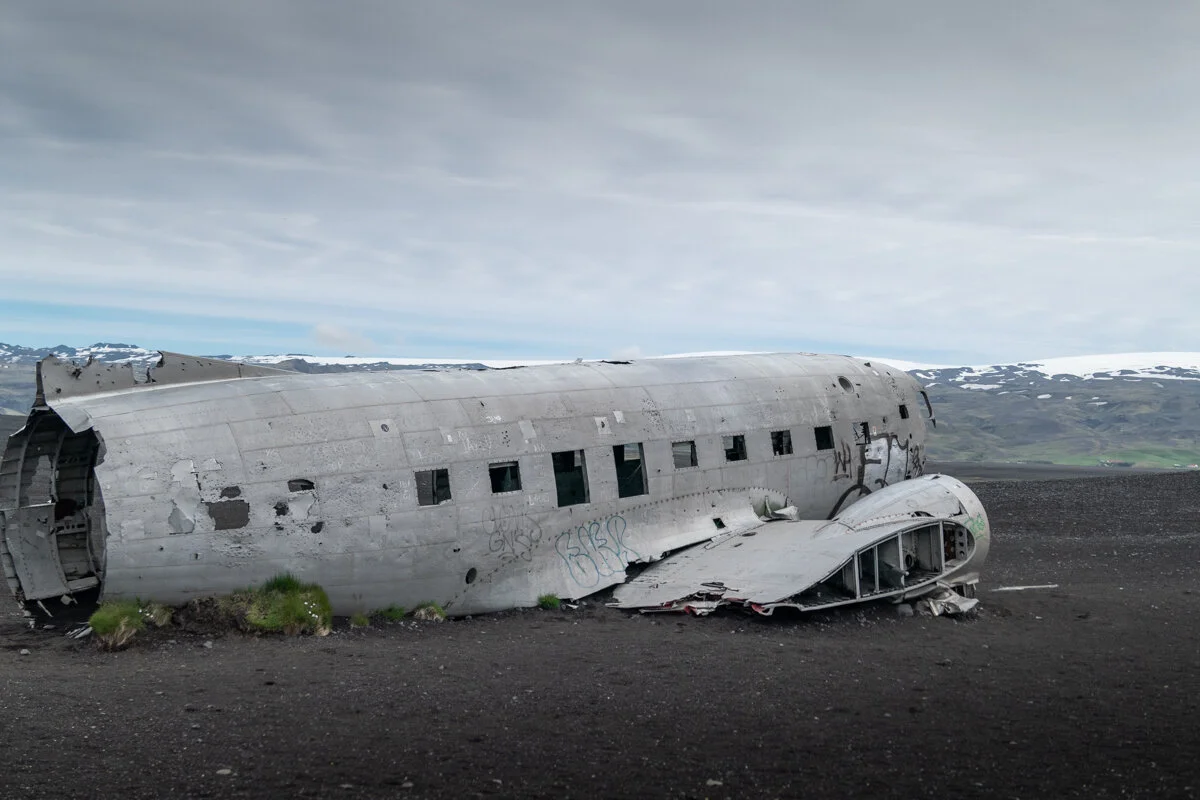 épave d'avion abandonnée sur une plage de sable noir