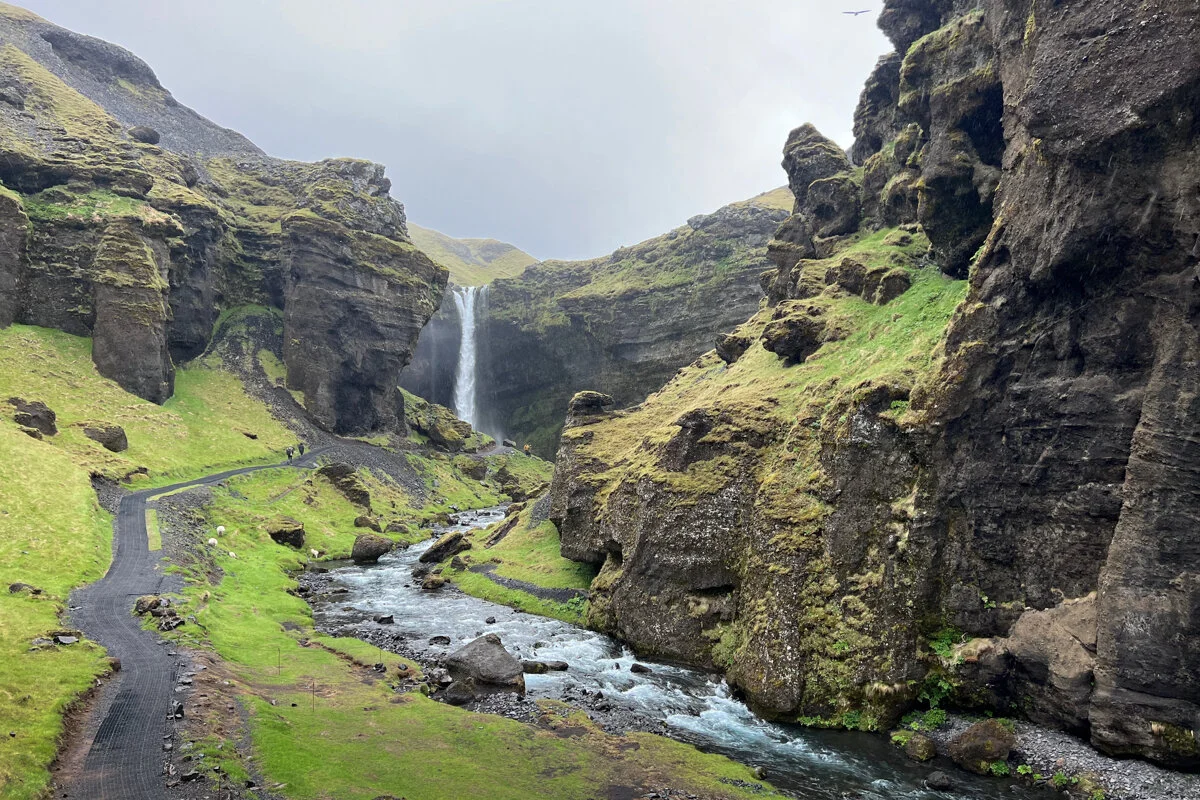 une cascade tombant dans une vallée verdoyante avec une rivière