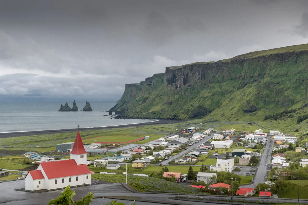 vue sur Vik depuis le cimetière, avec l'église, l'océan, le village et les falaises