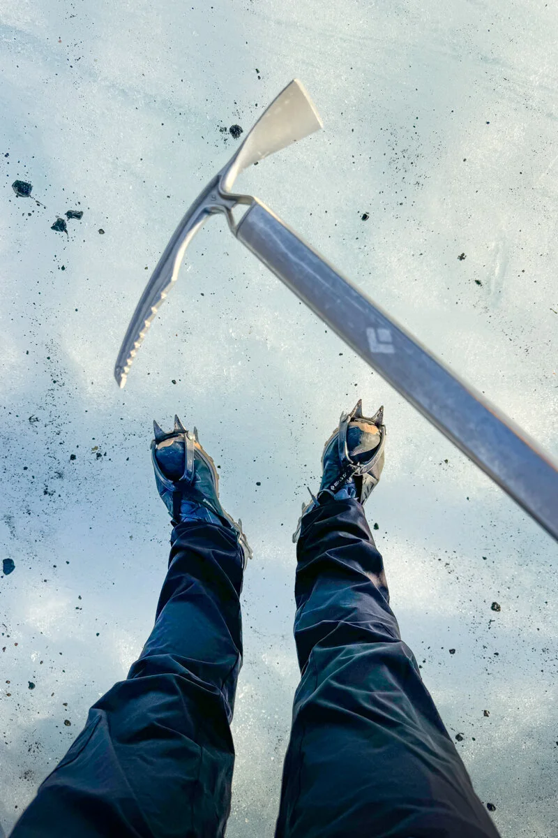 vue en plongée d'un piolet et de bottes sur la glace