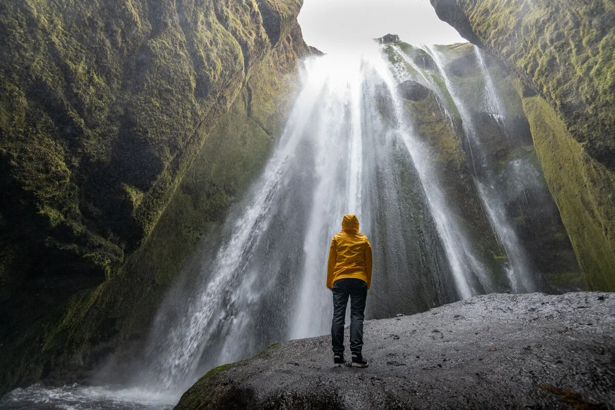 personne face à une cascade entourée de roche