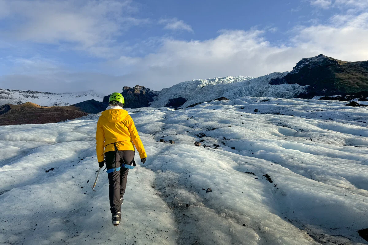 personne en veste jaune qui marche sur un glacier