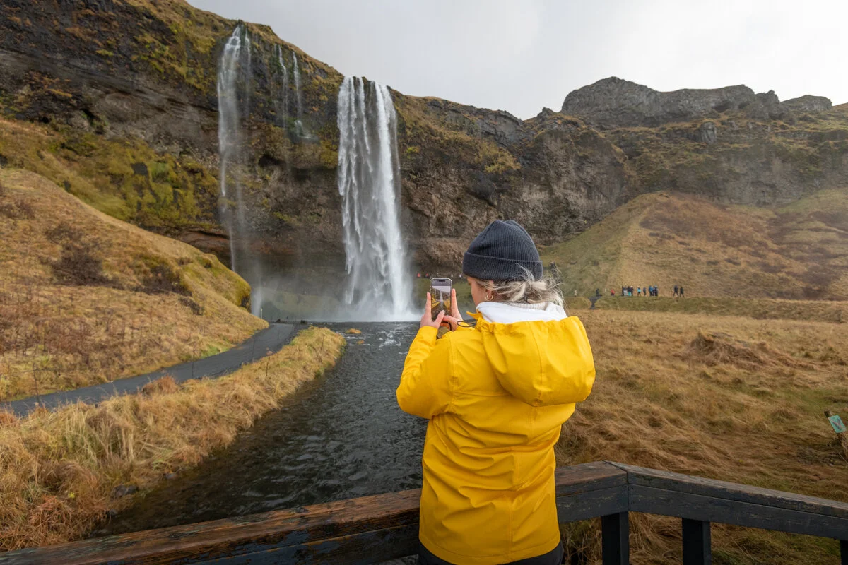 personne en ciré photographiant une cascade