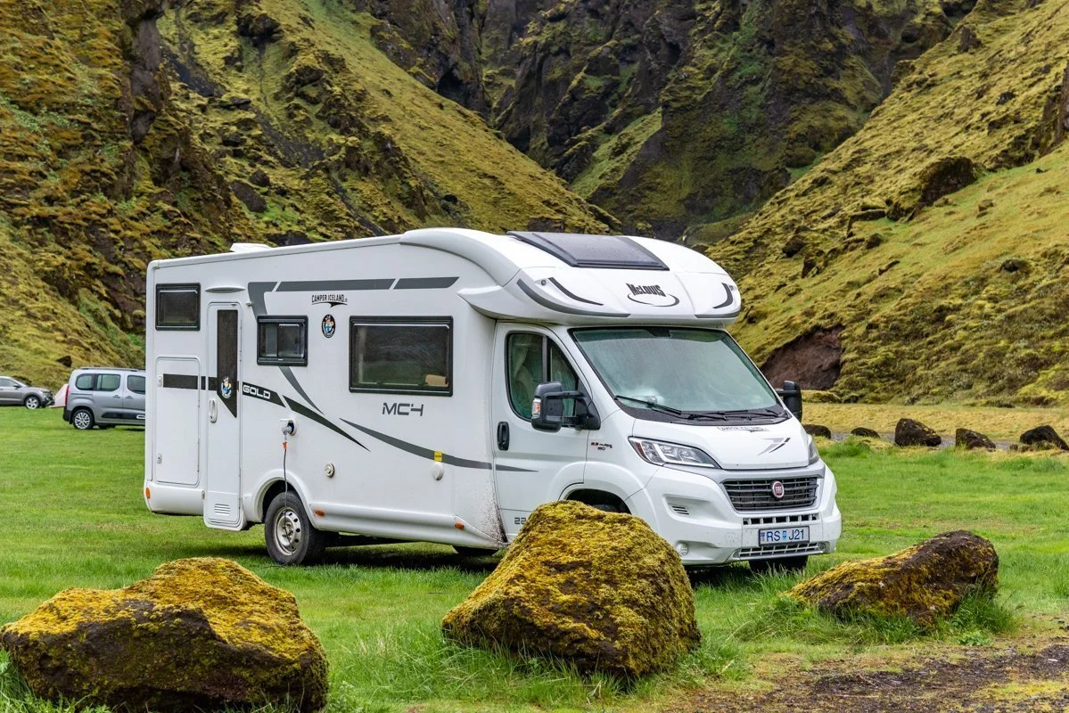 camping-car stationné sur l'herbe avec une montagne derrière