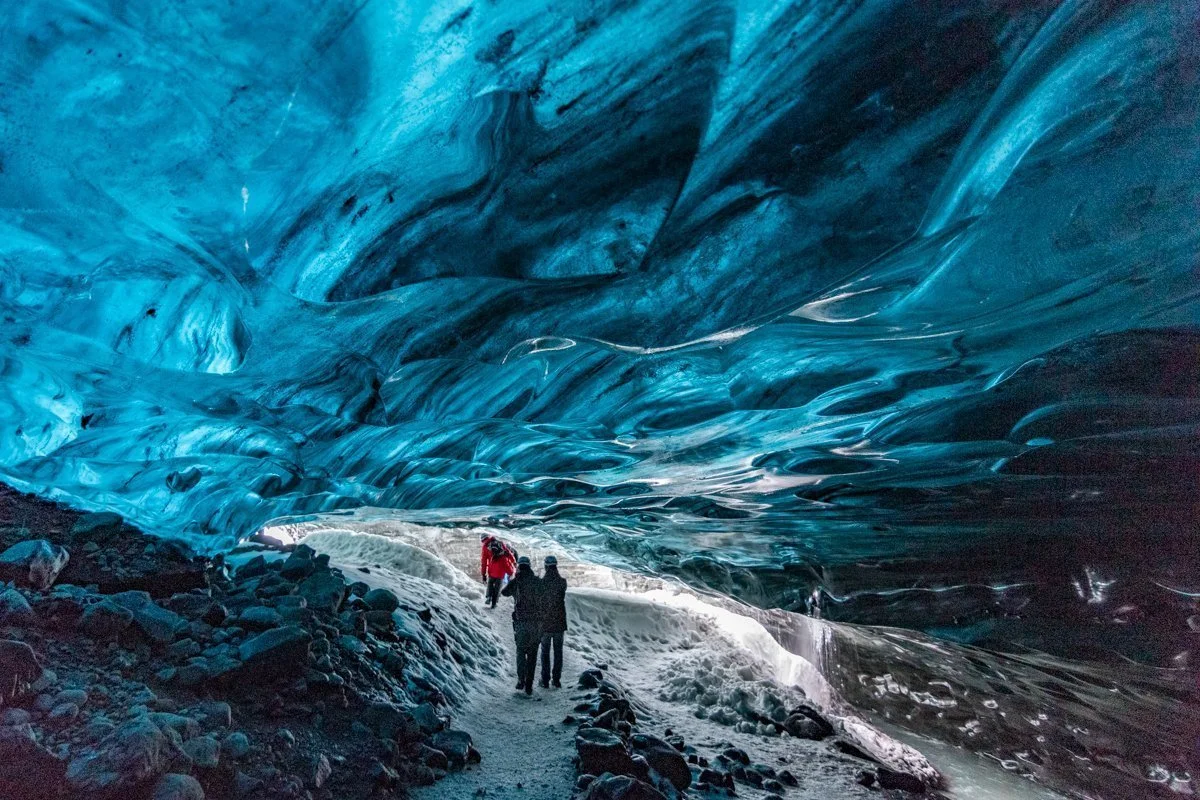 personnes dans une grotte de glace bleue sous un glacier
