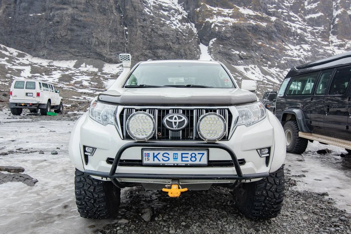 toyota land cruiser blanc tout terrain avec pare-buffle, vu de face dans un parking enneigé