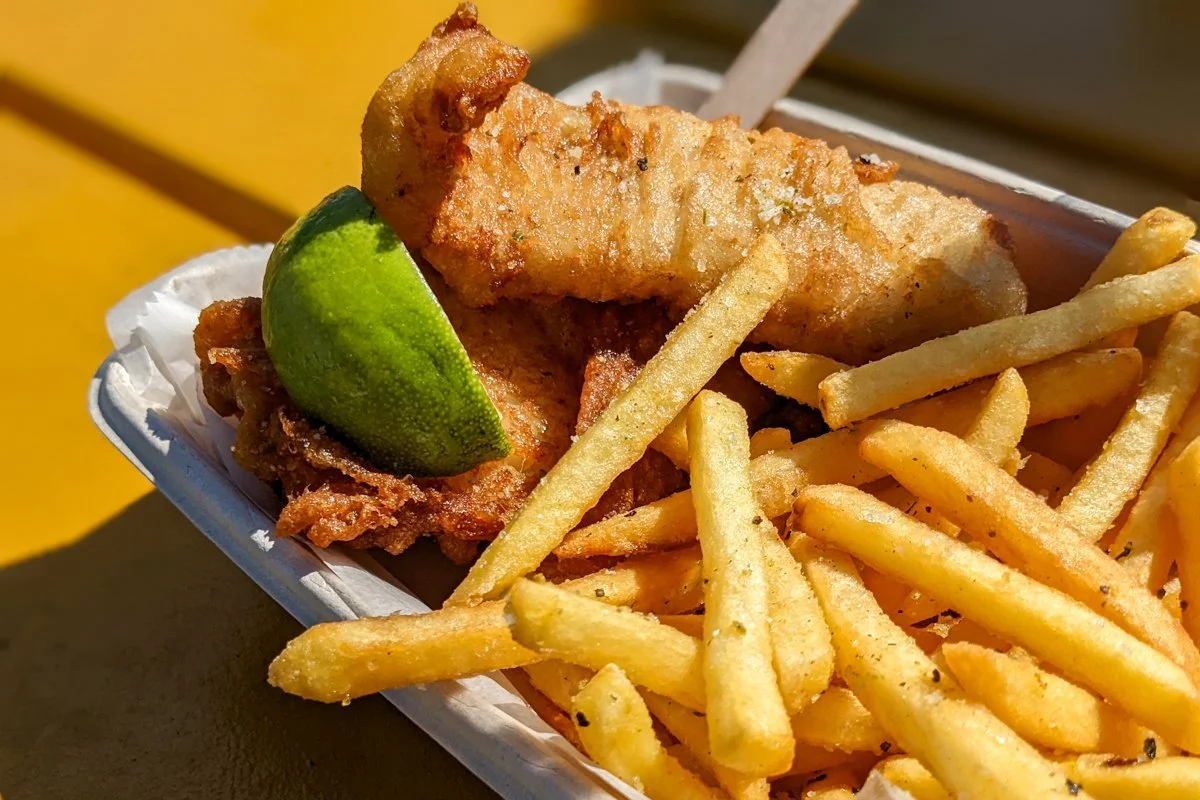 poisson frit avec frites et tranche de citron vert dans une barquette